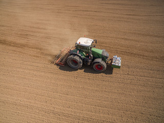 Aerial: ractor plows a agricultural field in spring and prepares it for sowing - aerial view