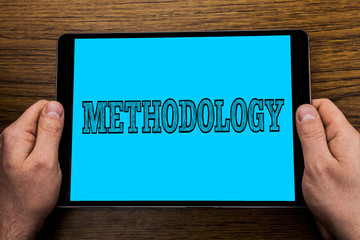 Text sign showing Methodology. Conceptual photo System of Methods used in a study or activity Steps to follow written on Tablet Screen holding in Hand on wooden background.