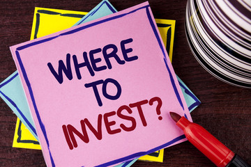 Word writing text Where To Invest Question. Business concept for Right Place Stock Share to spend your savings in written on Pink Sticky Note paper on wooden background Cup and Marker next to it