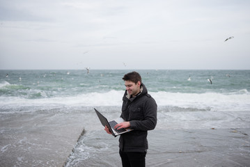 a man is standing on the beach and clapping a computer