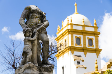 Fototapeta na wymiar Seville, Spain. Views of a headless statue in the Jardines de las Delicias public gardens, with the tower of the Pabellon de Argentina (Argentine Pavilion) of the Ibero-American Exposition of 1929