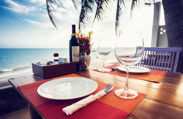 A romantic dinner in summer on a beach at sunset with two glasses of wine