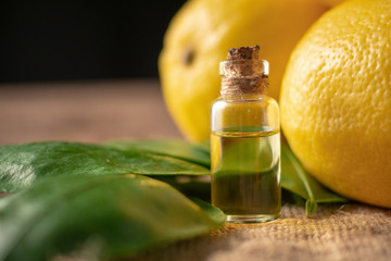 Bottles with Essential Oil of Lemon peel and leaf on wooden table
