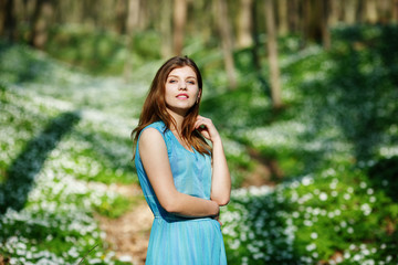 Relaxing woman at nature. Happy pretty young woman enjoying smell flowers over spring forest background