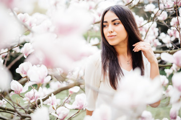 Beautiful young girl in a blooming garden with magnolias. Magnolia flowering, tenderness.