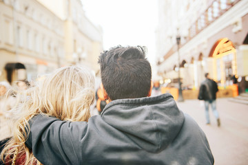 Young couple walking down the street. The guy hugs the girl.
