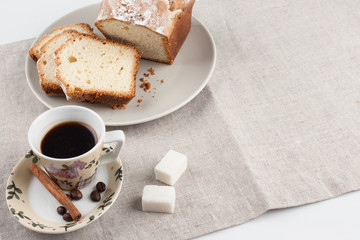 A Cup of coffee and a sliced cupcake on a linen tablecloth
