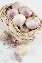 White garlic heads lying in a wicker basket on the table