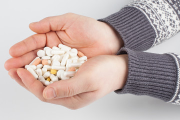 A handful of multi-colored tablets and pills in men's hands