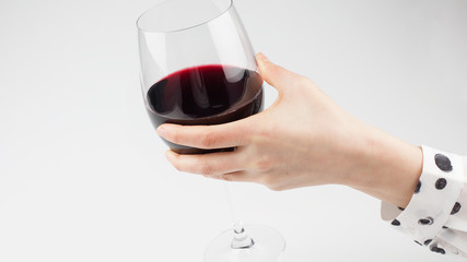 Female hand holding red wine glass on white background