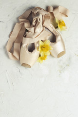 Pointe ballet shoes, Yellow Flower Narcissus on a light stone background. The concept of ballroom dancing