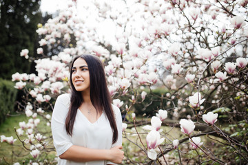 Young beauty caucasian woman near blossom magnolia tree flower outdoors