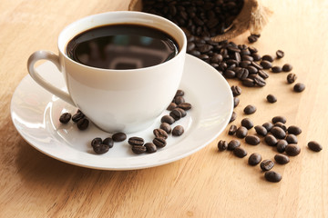 cup of black coffee with sack of coffee beans on wood desk