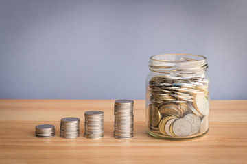 stack of coin and coin in grass jar, concept saving money