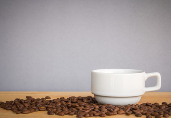 white coffee cup with coffee beans on wood desk 