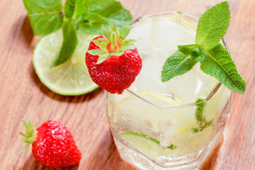 A glass of cold water with lemon and lime, ice cubes and mint leaves