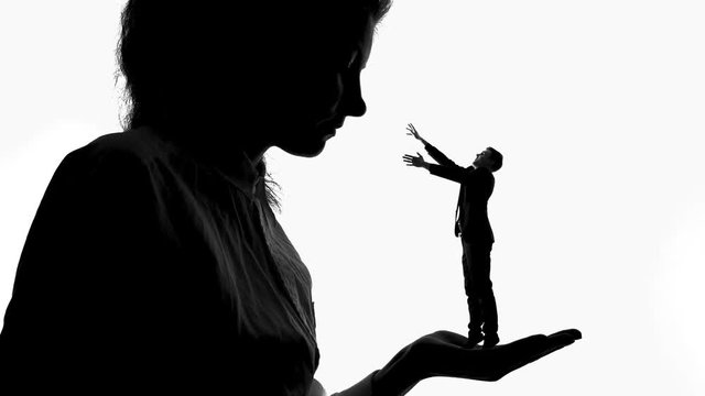Shadow of female holding tiny man in love in hand, women power, domination