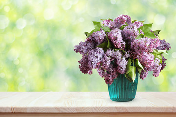 Bouquet of lilacs on a wooden table. Flowers in a vase.