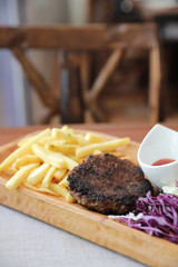 Beef cutlet for steak with fires and vegetables on wood background