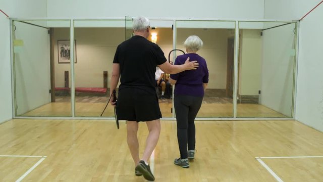 Mature couple replacing senior couple on a squash court