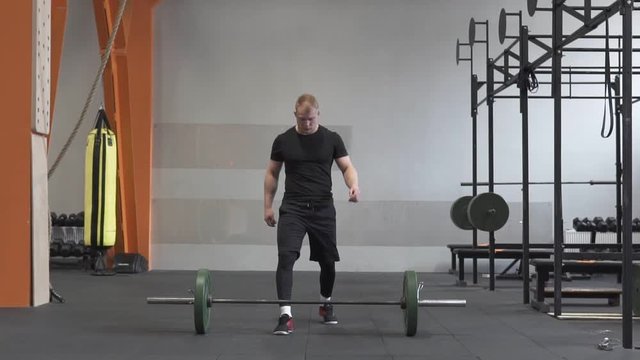 Male athlete doing barbell snatch exercise in cross fit gym
