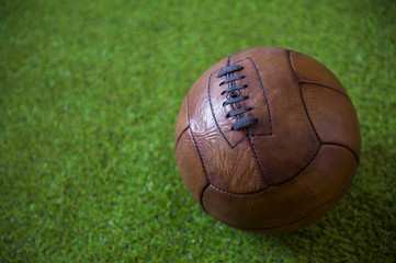 Close up view of a vintage, brown leather (circa 1930s) football on lush green grass background