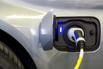Close up of the Hybrid car electric charger station with power supply plugged into an electric car being charged.