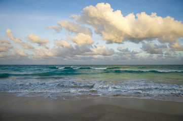 Waves of tropical turquoise sea crashing on the beach at dusk