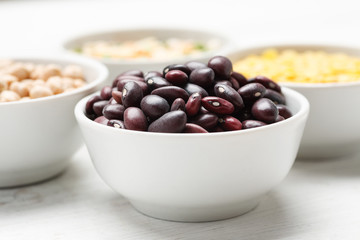 Different beans in bowls on a white wooden table