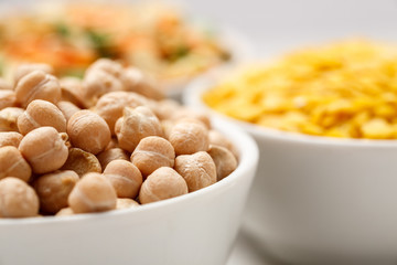 Chickpea and other beans in white bowls on a wooden table