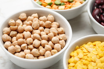 Chickpea and other beans in white bowls on a wooden table