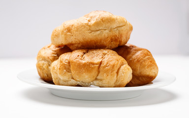 Fresh croissant in a white plate on a white table