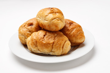 Fresh croissant in a white plate on a white table