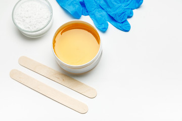 Wax for depilation with blue gloves and other tools on a white background, flat lay, text space
