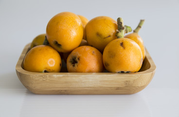 isolated yellow plums on the wooden plate.