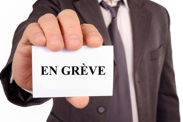 Homme tenant une carte sur laquelle est &eacute;crit en gr&egrave;ve 