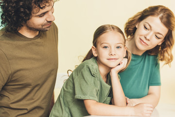 cropped shot of parents looking at adorable little daughter smiling at camera