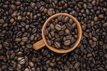 Cup of coffee beans on coffee background