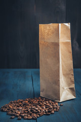 scattered coffee beans from kraft packaging on a blue, wooden background, top view