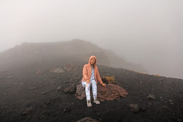 The girl on Mount Etna. The Etna volcano crater. Black Volcanic Earth, Volcanic Lava and Stones. ...