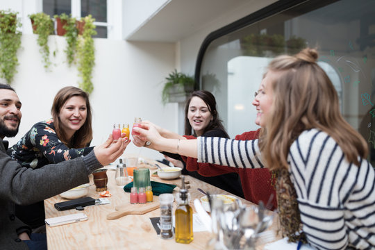 Happy friends toasting with healthy juices at table