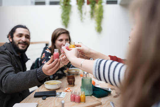 Friends toasting with healthy juices at table
