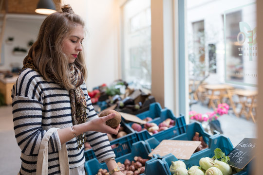 Young woman buying vegetables at organic market.