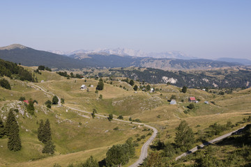 Fototapeta na wymiar Hilly landscape with houses and a street in Durmitor National Park in Dinaric Alps, Montenegro