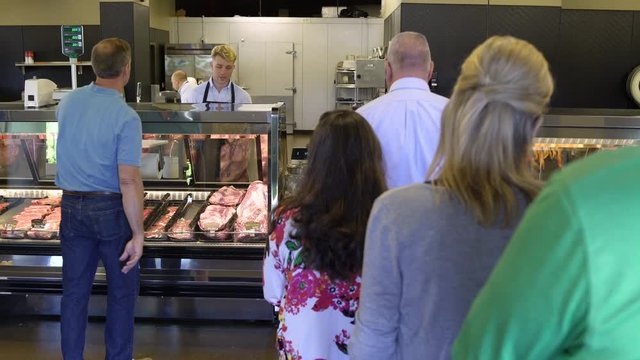 Customers standing in line in a butcher shop
