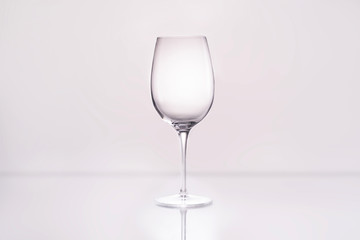 empty wineglass on reflective surface and on white