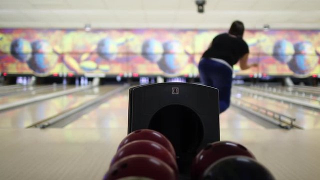 Playing Bowling Game. Young woman throwing a ball in the bowling lane