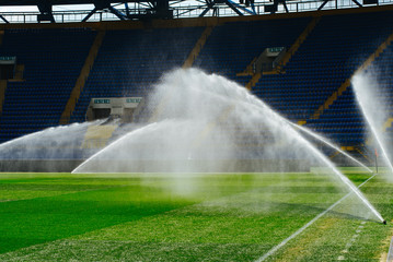 Irrigation turf. Sprinkler watering football field. System working on fresh green grass on football or soccer stadium.