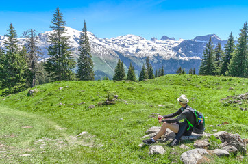 Fototapeta na wymiar Swiss Alps. A man sitting on a green meadow, admiring the mountain scenery. Engelberg Resort