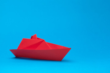 Origami paper boat on blue background